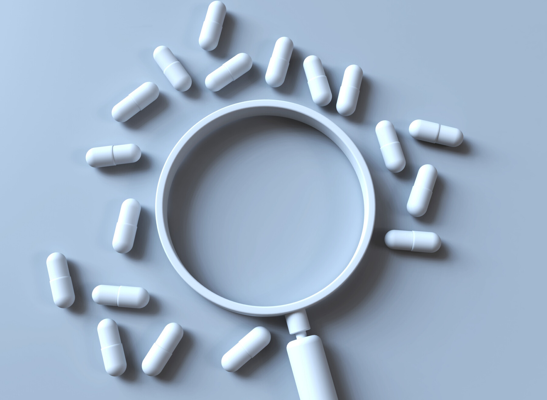 A magnifying glass is surrounded by a scattering of pills.