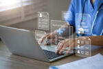 A doctor uses a laptop to manage electronic medical records.