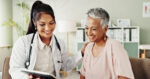 A doctor and a patient smile as they look at a tablet.