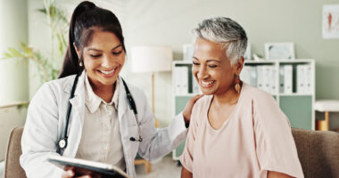 A doctor and a patient smile as they look at a tablet.
