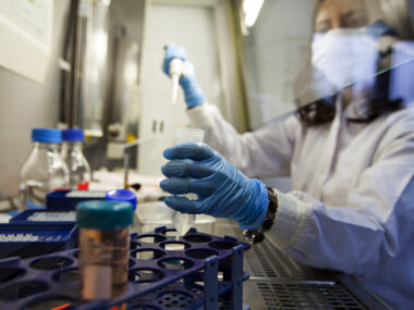 A photo shows a scientist holding a vial in a lab.