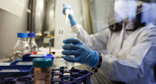 A photo shows a scientist holding a vial in a lab.