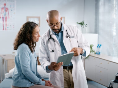 A doctor shows information on a tablet to a patient.
